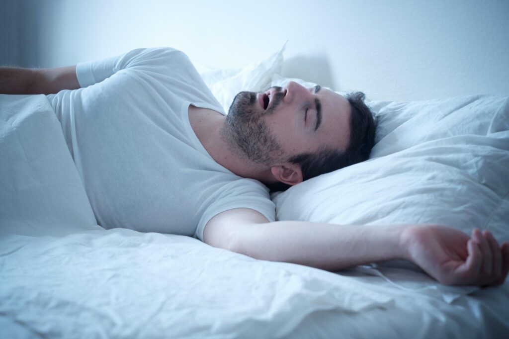 Person lying on a bed wearing a white t-shirt