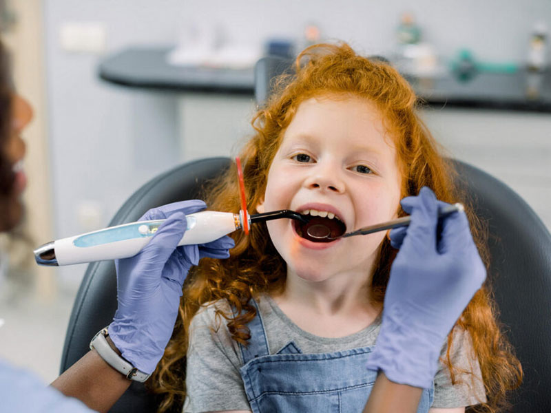 Dental professional using a curing light on a patient during a dental procedure